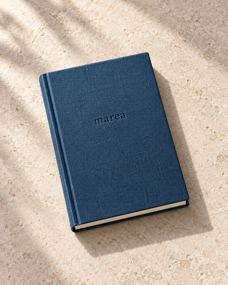 Cuaderno de bolsillo Marea A6 de lino azul mineral sobre piedra clara.